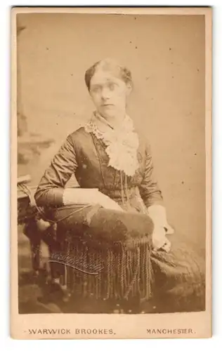 Fotografie Warwick Brookes, Manchester, Dame mit Spitzenschleife am Kragen auf Stuhl sitzend
