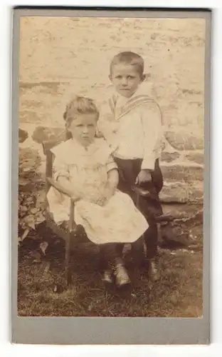 Fotografie unbekannter Fotograf und Ort, Portrait kleiner Junge im Matrosenhemd und sitzendes Mädchen