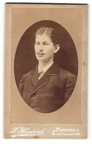 Fotografie F. Heinrich, Torgau, Junger Mann mit hochgedrehtem Schnauzbart trägt dunkle Jacke und weisses Hemd