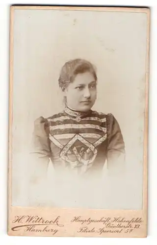 Fotografie H. Wittrock, Hamburg, JUnge Dame mit zurückgebundenen Haaren trägt Kleid mit aufwendigen Stickereien