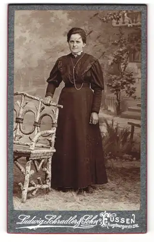 Fotografie Ludwig Schradler & Sohn, Füssen, Portrait einer Dame in schwarzem klassischem Kleid stehend