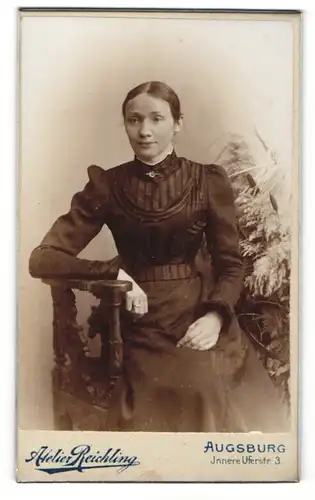 Fotografie Reichling, Augsburg, Portrait einer schönen Dame in festlichem schwarzen Kleide sitzend