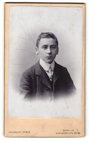 Fotografie Wilhelm Stein, Berlin, Portrait eines Jungen in dunklem Anzug mit schönem weissem Rundkragen