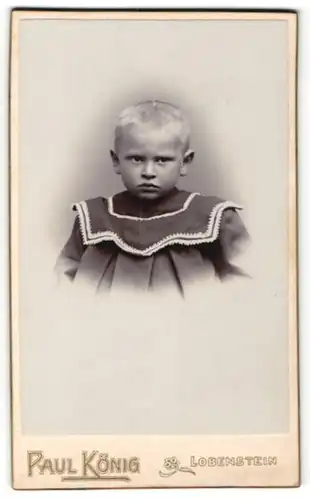 Fotografie Paul König, Lobenstein, Kleiner Junge mit blonden kurzen Haaren trägt ein dunkles Kleid mit Verzierungen