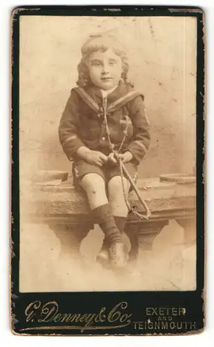 Fotografie E. Denney & Co., Exeter, Portrait niedliches kleines Mädchen im Matrosenanzug
