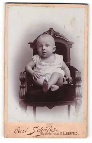 Fotografie Carl Schäfer, Elberfeld, Kleinkind in weissem Kleidchen sitzt auf Sessel