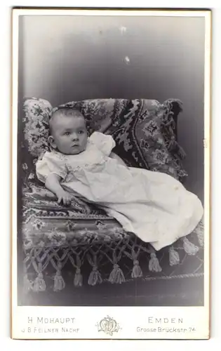 Fotografie H. Mohaupt, Emden, Kleinkind in gepufftem Hemdchen liegt auf Sessel