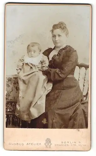 Fotografie Globus Atelier, Berlin-S, Portrait stolze Mutter im hübschen Kleid mit Baby auf dem Arm