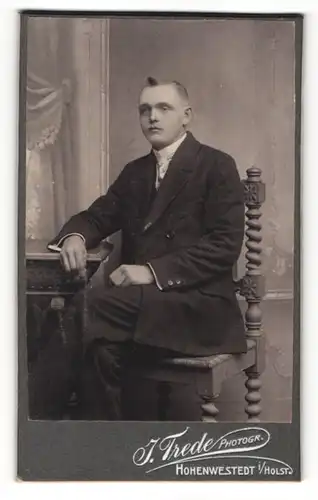Fotografie J. Trede, Hohenwestedt i / Holst., Portrait junger Herr im Anzug am Tisch sitzend