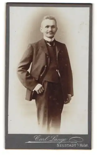 Fotografie Carl Lange, Neustadt i/Holst., Mann mit hochgestellten Haaren und Schnurrbart trägt dunklen Anzug