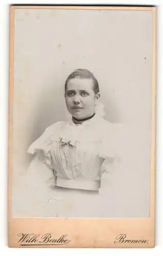 Fotografie Wilhelm Beulke, Bremen, Portrait einer hübschen Frau in weissem Rüschenkleid und schwarzem Halsband