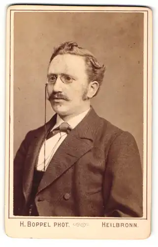 Fotografie Heinrich Boppel, Heilbronn, Portrait eines schönen Herren in feinem Anzug mit Fliege und edler Brille