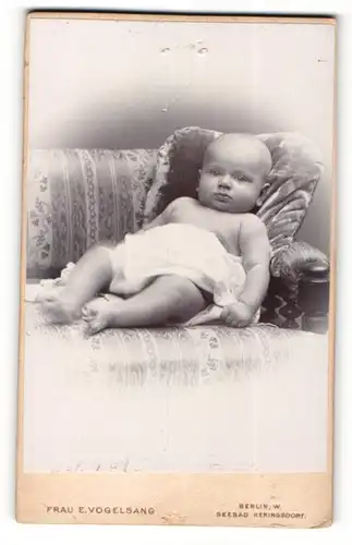 Fotografie E. Vogelsang, Berlin-W., Portrait liegendes Baby im weissen Hemd mit nackigen Füssen