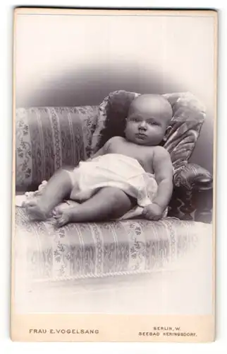 Fotografie E. Vogelsang, Berlin-W., Portrait liegendes Baby im weissen Hemd mit nackigen Füssen