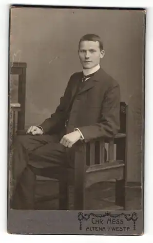 Fotografie Chr. Hess, Altena i/Westf., Portrait eines schönen jungen Mannes in schwarzem Anzug sitzend
