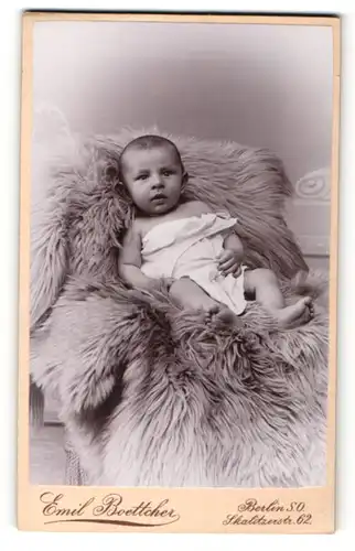 Fotografie Emil Boettcher Berlin, Portrait niedliches Baby im weissen Hemd auf Fell sitzend