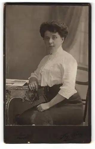 Fotografie Sig. Bing, Wien, Junge Frau mit Bluse und hochgestecktem Haar an Tisch lehnend