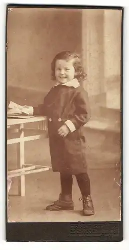 Fotografie Ernst Stautz, Eschwege, Kleines Kind im Mantel am Tisch lehnend