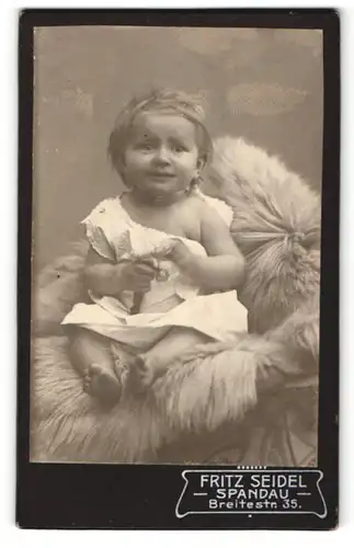 Fotografie Fritz Seidel, Berlin-Spandau, Portrait sitzendes Kleinkind im weissen Hemd mit Spielzeug
