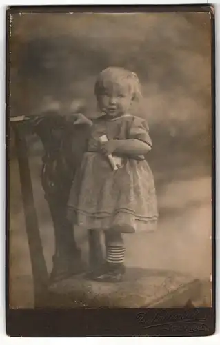 Fotografie D. Vahlendick, Kellinghusen, Portrait Kleinkind auf Sitzmöbel stehend