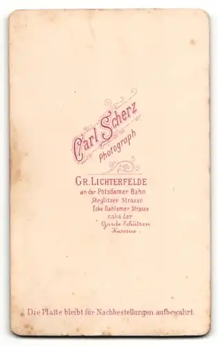 Fotografie Carl Scherz, Gr. Lichterfelde, Portrait niedlicher kleiner Bube im Hemdchen auf Fell sitzend