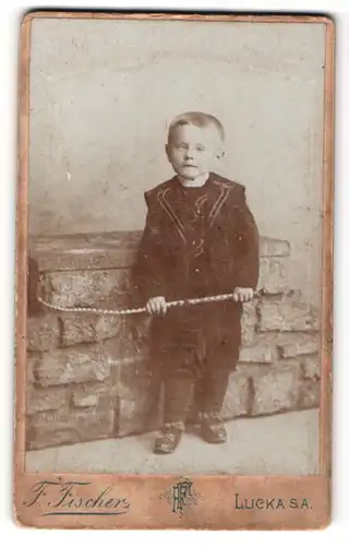 Fotografie F. Fischer, Lucka / S. A., Portrait kleiner Junge in hübscher Kleidung mit Peitsche