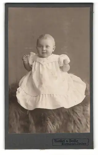 Fotografie Nöthel & Deike, Hannover-Linden, Portrait lachendes süsses Kleinkind im weissen Kleidchen