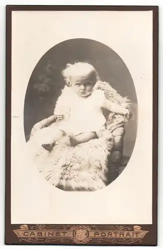 Fotografie Cabinet Portrait, unbekannter Ort, Portrait niedliches Kleinkind im weissen Hemd auf Fell sitzend