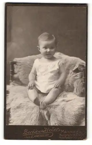 Fotografie Berliner Atelier E. Kregeloh, Mannheim, Portrait lachendes Kleinkind auf einem Fell sitzend