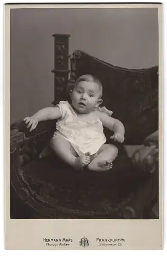Fotografie Hermann Maas, Frankfurt a. M., Brönnerstr. 26, Niedliches Kleinkind im Kleid auf einem Stuhl sitzend