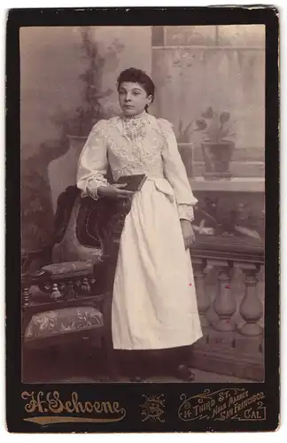 Fotografie H. Schoene, San Francisco, 14 Third St., Junge Frau in langem Kleid an einem Stuhl anlehnend