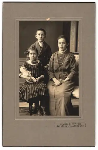 Fotografie Alwin Dietrich, Glauchau, Mutter in Trachtenkleid mit Sohn im Anzug und Tochter mit Puppe