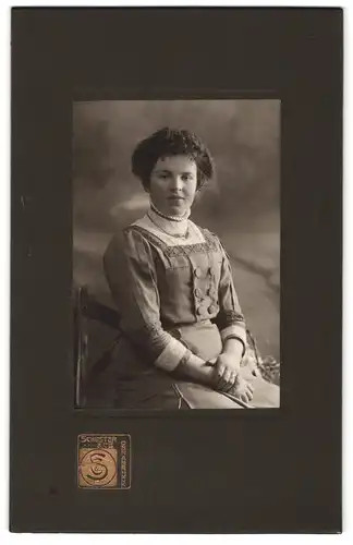 Fotografie Schuster, Osnabrück, Elegante Frau im Trachtenkleid mit lockiger Frisur, Halskette und Ring am Finger