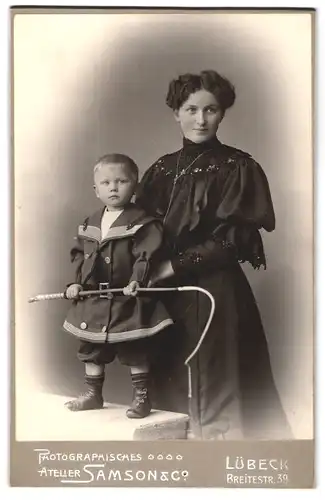 Fotografie Atelier Samson & Co., Lübeck, Breitestr. 39, Mutter neben Jungen im Matrosenanzug mit Peitsche in der Hand