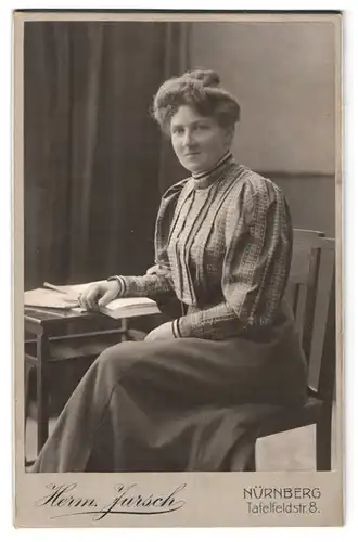 Fotografie Herm. Jursch, Nürnberg, Tafelfeldstrasse 8, Portrait bürgerliche Dame mit Buch am Tisch sitzend