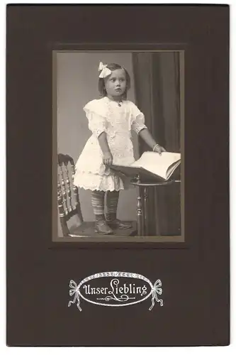 Fotografie unbekannter Fotograf und Ort, Portrait kleines Mädchen im weissen Kleid mit einem Buch