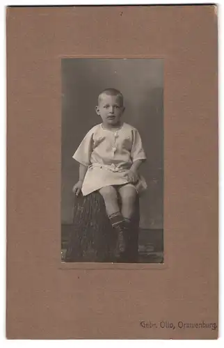 Fotografie Gebr. Otto, Oranienburg, Kleiner Junge posiert auf einem Baumstamm