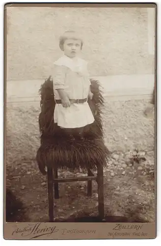 Fotografie Adalbert Hering, Zeillern, Kleinkind in heller Kleidung steht auf einem Stuhl