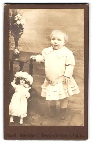 Fotografie Karl Becker, Gernsheim a. Rh., Portrait kleines Kind in weissem Kleid mit Puppe