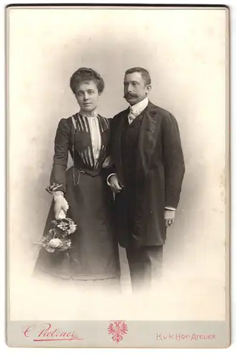 Fotografie C. Pietzner, Wien, Mariahilferstrasse 3, Portrait bürgerliches Paar in eleganter Kleidung mit Blumen