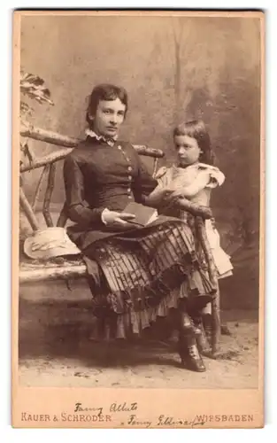 Fotografie Kauer & Schröder, Wiesbaden, Taunusstrasse 47, Portrait hübsch gekleidete Dame mit Buch und Mädchen