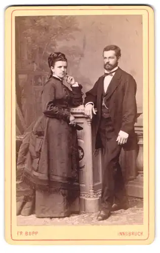 Fotografie Friedrich Bopp, Innsbruck, Portrait elegant gekleidetes Paar an Sockel gelehnt