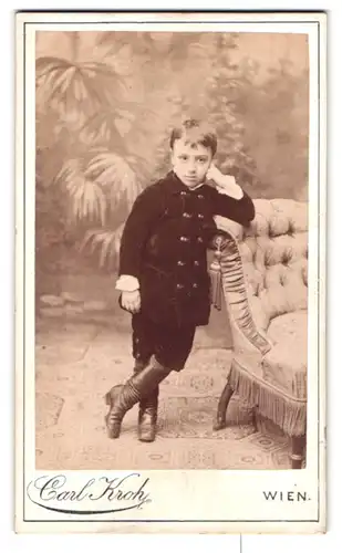 Fotografie Carl Kroh, Wien-Josefstadt, Piaristengasse 20, Portrait hübsch gekleideter Junge an Sessel gelehnt
