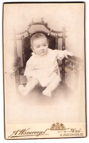 Fotografie Arnold Wasservogel, Wien, Radetzkystrasse 12, Portrait niedliches Kleinkind im weissen Hemd auf Stuhl sitzend