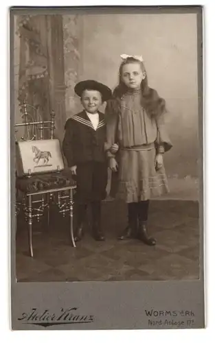 Fotografie Atelier Kranz, Worms a. Rh., Nord-Anlage 17 I., Portrait hübsch gekleidetes Mädchen und Brüderchen mit Ranzen