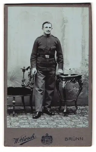 Fotografie W. Hirsch, Brünn, Franzens-Glacis 5, Portrait österreichischer Soldat in Unifrom mit Bajonett, Schirmmütze