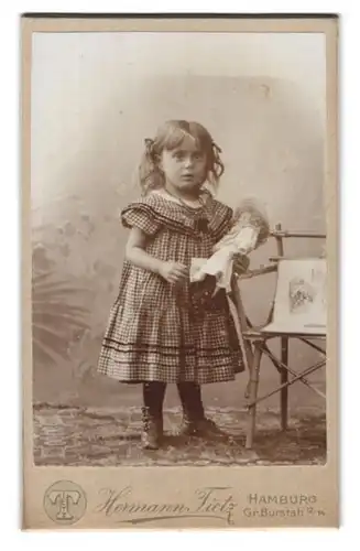 Fotografie Hermann Tietz, Hamburg, Gr. Burstah 12 /14, Portrait Mädchen im Karokleid mit Puppe, Bambusstuhl