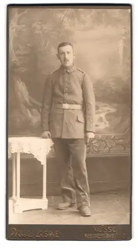 Fotografie Paul Laske, Neisse, Berlinerstr. 13, Portrait Soldat in Feldgrau Uniform steht im Atelier