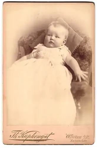 Fotografie Th. Kaphengst, Witten a. R., Bahnhofstrasse, Portrait niedliches Kleinkind im weissen Kleid auf Sessel sitzend