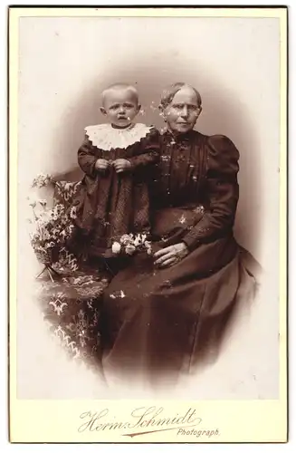 Fotografie Herm. Schmidt, Berlin, Portrait ältere Dame im schwarzen Kleid mit Kleinkind